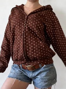 Detail of a brown polka dot hooded jacket with zipper closure and front pockets