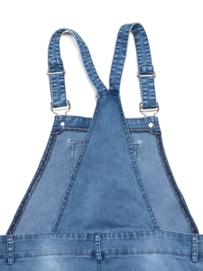 Detail of adjustable metal buckles and stitching on classic blue wash denim overall dress