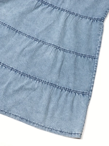 Detail of light blue tiered denim skirt showing washed cotton texture and tiered seams