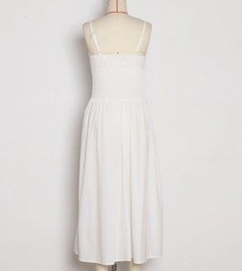 Dettaglio del retro elasticizzato a punto smock sul maxi abito bianco a trapezio