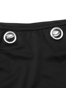 Primer plano de la falda negra con aberturas, ojales metálicos plateados y costuras finas