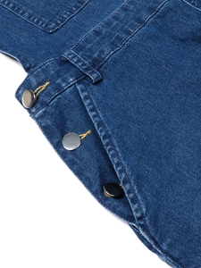 Dettaglio dell'abito scamiciato in denim blu scuro con bottoni metallici e cuciture gialle