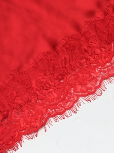 Detail of red silky satin fabric featuring exquisite floral lace with eyelash trim edge