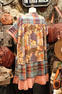 Detail of vintage patchwork dress with floral print and plaid layers on a mannequin