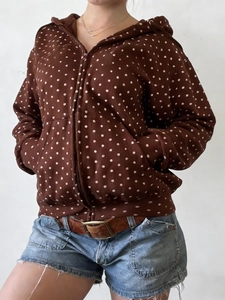 Detail view of a brown polka dot zip-up hoodie featuring pockets and a drawstring hood