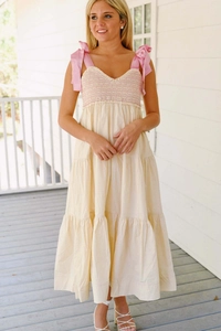 Détail du bustier froncé rose et robe midi crème à volants avec nœuds aux épaules