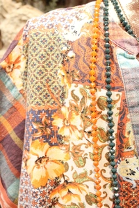 Detail of V-neck tunic featuring bohemian floral prints and layered beaded necklaces