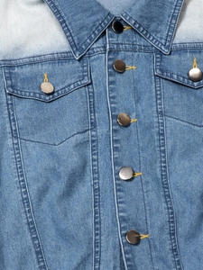 Detail of blue washed denim dress featuring metal buttons and contrast stitching on pockets