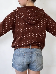 Women's brown polka dot hooded jacket paired with light blue denim shorts and brown belt