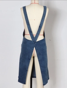 Detail view of washed denim dress featuring cross-back straps and center back slit
