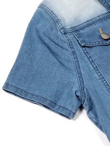 Detail of light blue denim dress showing yellow stitching and metallic pocket buttons