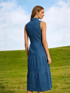 Robe en jean sans manches bleu foncé avec boutons et jupe à volants sur fond de pelouse verte