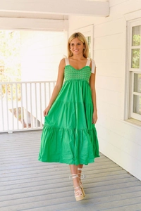 Détail d'une robe d'été verte à volants avec bustier smocké et bretelles à nœuds blancs