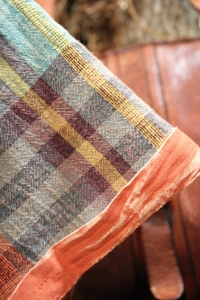 Close-up detail of multi-color plaid fabric texture with vibrant orange edge piping