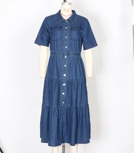 Dettaglio dell'abito in denim blu scuro con gonna a balze e chiusura con bottoni