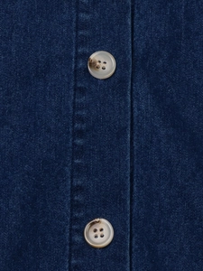 Détail de deux boutons ambrés sur un tissu en denim bleu foncé de haute qualité