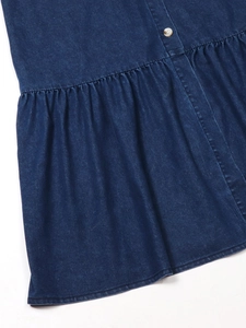 Détail d'une robe en jean bleu foncé avec ourlet à volants et boutons métalliques
