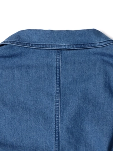 Gros plan du col en V d'une robe en jean montrant le sergé indigo et la qualité de couture