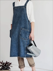 Full view of washed denim apron dress with large double pockets and back straps