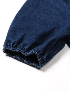 Détail des poignets élastiques en jean bleu foncé avec coutures soignées et volants