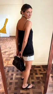 Mirror selfie showing a black spaghetti strap camisole with delicate lace trim at the hem