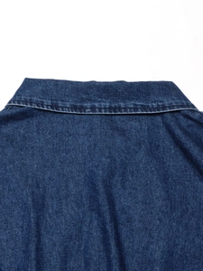 Dettaglio del colletto a punta e della trama del tessuto denim blu scuro di questo abito