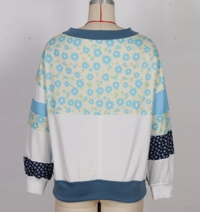 Detail of color-block sweatshirt featuring blue daisy floral patterns and ribbed trims