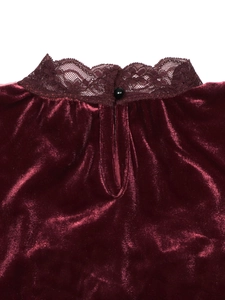 Detailed view of the burgundy velvet neckline with lace trim and black button accent