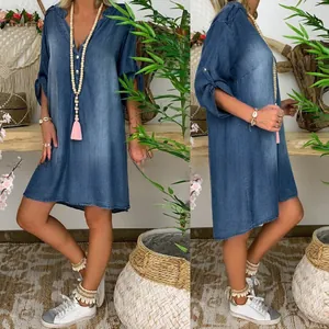 Dettaglio dello scollo a V con bottoni decorativi su abito in denim lavato blu donna