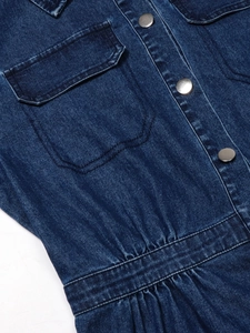 Dettaglio vestito di jeans blu scuro con bottoni metallici, tasche a patta e pieghe in vita