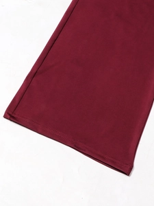 Detail of burgundy jumpsuit hem with professional double-needle stitching and fabric texture
