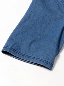 Détail des doubles coutures sur le revers d'une robe en jean bleu avec col en V