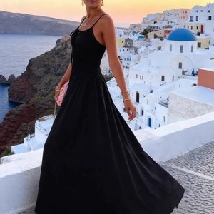Elegant black maxi dress with spaghetti straps and tie-front against Santorini backdrop
