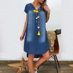Detail of the washed denim blue dress featuring a V-neckline and irregular curved hemline