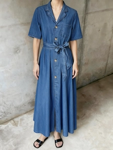 Détail d'une robe longue en jean bleu avec boutons en bois et ceinture à nouer