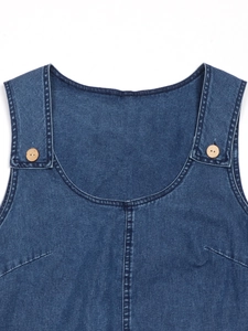 Detailed close-up of dark blue denim dress with wide straps and wooden button accents