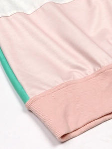 Detail shot of color-block knit sweater with pink ribbed hem and soft mint fabric