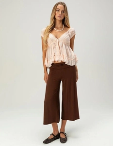 Detail shot of women's casual pink ruffle top and high waist brown wide-leg trousers outfit