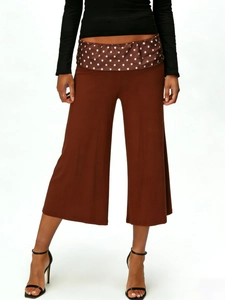 Detail view of brown wide-leg cropped pants with retro polka dot waistband accents