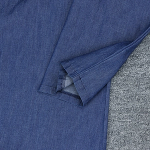 Détail de l'ourlet de la robe en jean montrant des coutures de qualité et la texture du tissu