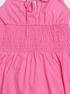 Dettaglio vestito estivo rosa con vita arricciata a nido d'ape e laccetti sulla scollatura
