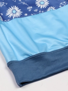 Detail of striped knit sweater with daisy floral print and blue patchwork ribbed hem