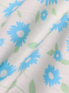 Detailed macro view of soft white knit fabric featuring light blue daisy floral prints