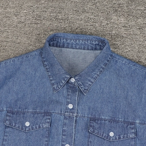 Dettaglio del colletto dell'abito in denim con bottoni bianchi e tasche sul petto