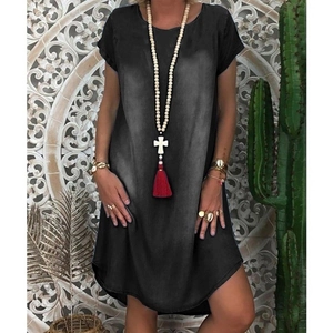 Detail of a loose black denim dress with bohemian cross necklace and ethnic jewelry