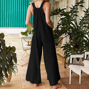 Detail of loose black overall jumpsuits featuring back pleats and wide leg design