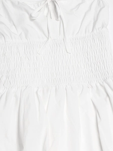 Dettaglio dell'abito in cotone bianco con scollo a fiocco e design della vita a punto smock