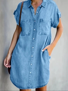 Detail view of light blue denim shirt dress featuring chest pockets and white buttons