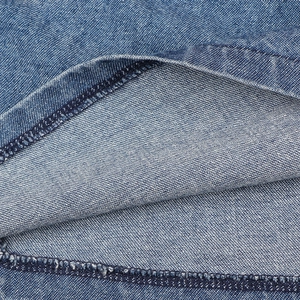 Vista macro del tessuto denim blu che mostra la trama saia e i dettagli della doppia cucitura