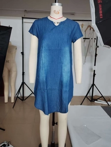 Detail view of blue denim dress featuring short sleeves and a stylish curved hemline